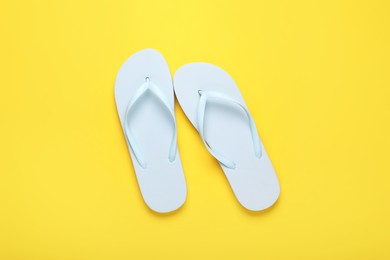 Photo of Stylish white flip flops on yellow background, top view