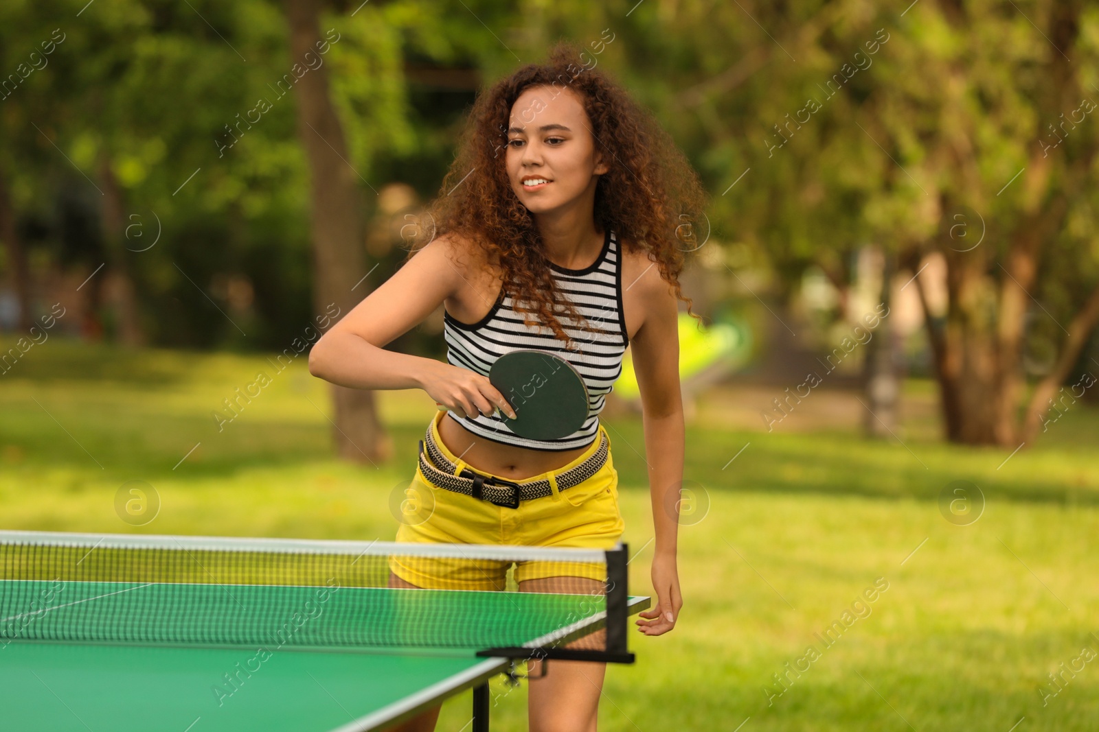 Photo of Young African-American woman playing ping pong outdoors