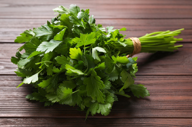 Photo of Bunch of fresh green parsley on wooden table, closeup