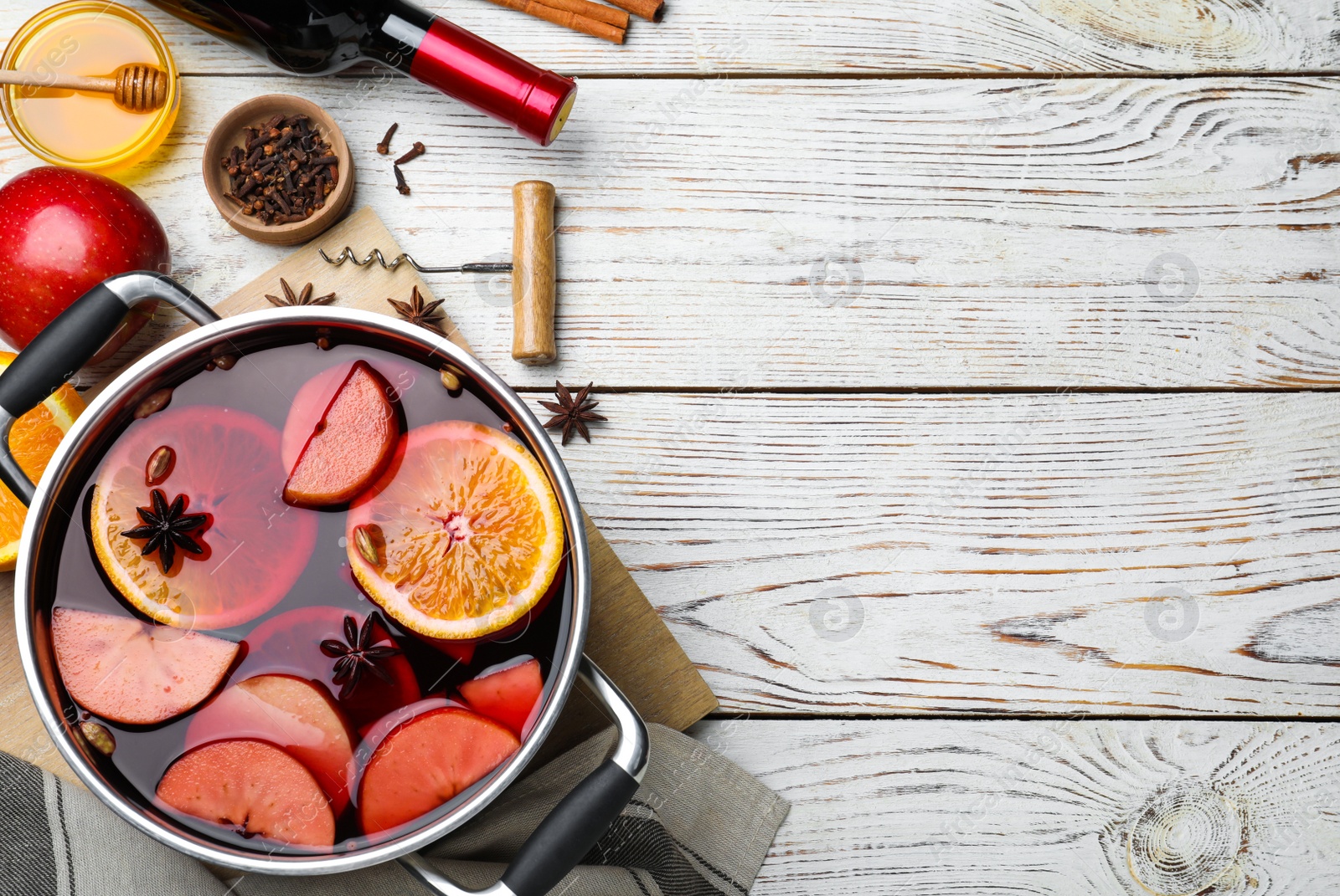 Photo of Delicious mulled wine and ingredients on white wooden table, flat lay. Space for text