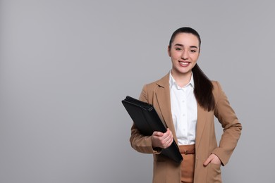 Happy real estate agent with leather portfolio on grey background. Space for text