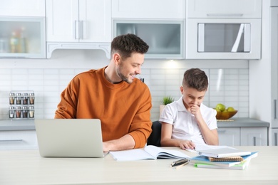 Dad helping his son with homework in kitchen