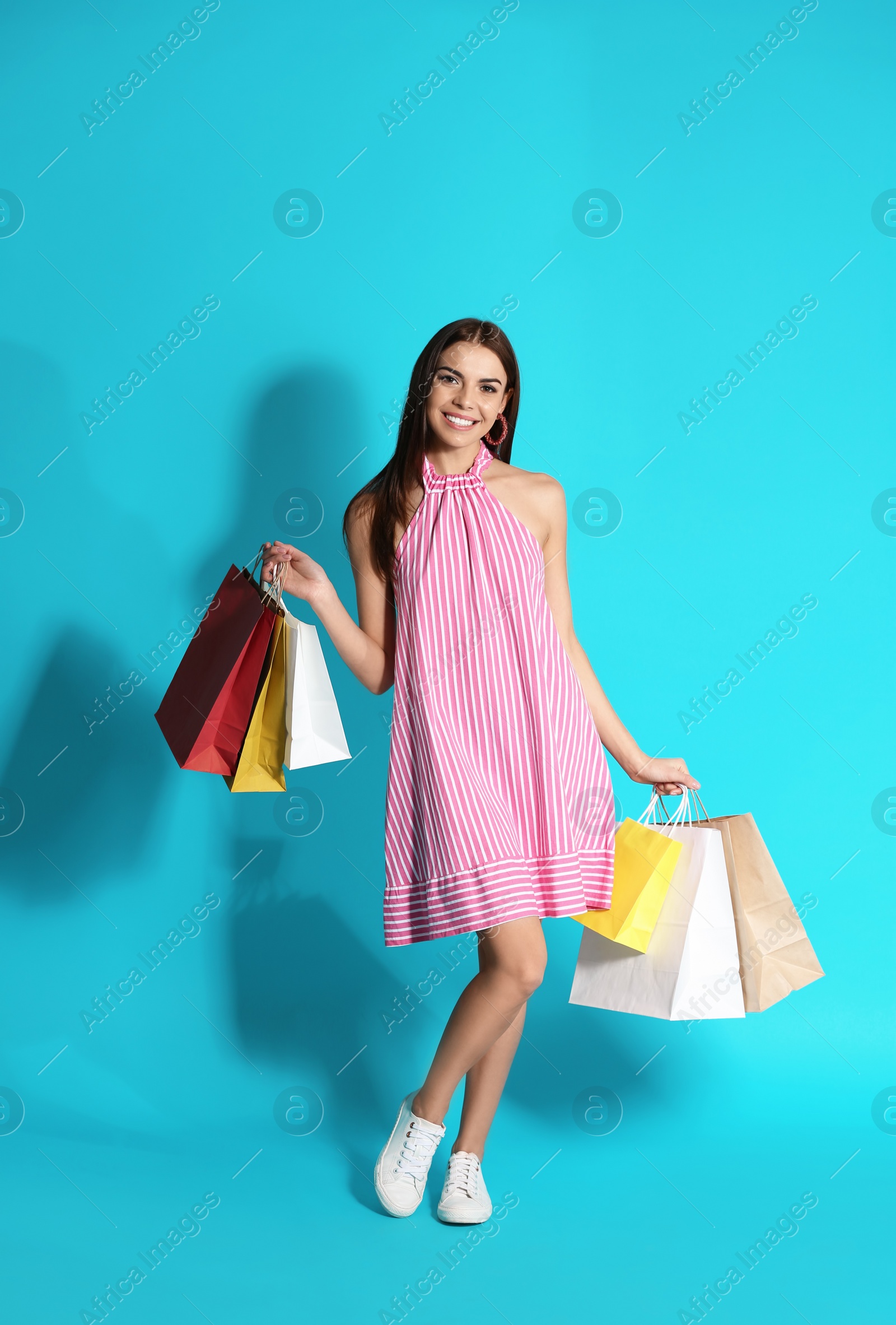 Photo of Young woman with shopping bags on color background