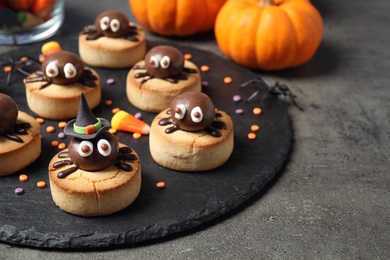 Photo of Delicious biscuits with chocolate spiders on grey table. Halloween celebration