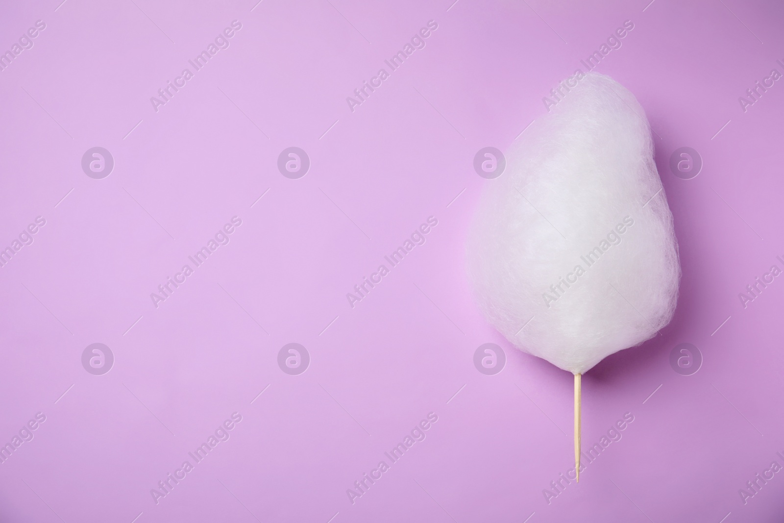 Photo of Sweet cotton candy on violet background, top view. Space for text