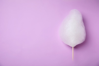 Photo of Sweet cotton candy on violet background, top view. Space for text