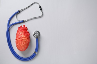 Photo of Stethoscope, heart model on grey background, flat lay with space for text. Cardiology concept