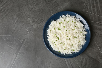 Photo of Plate of boiled rice on grey background, top view with space for text