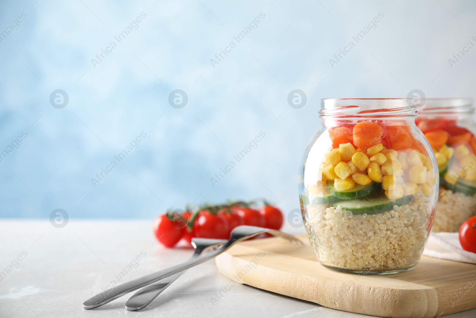 Photo of Jars with healthy quinoa salad and vegetables on table. Space for text