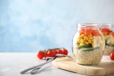 Photo of Jars with healthy quinoa salad and vegetables on table. Space for text