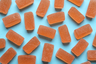 Tasty orange jelly candies on light blue background, flat lay