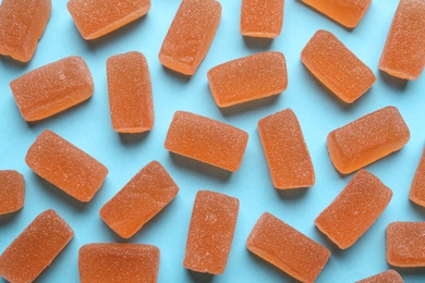 Photo of Tasty orange jelly candies on light blue background, flat lay