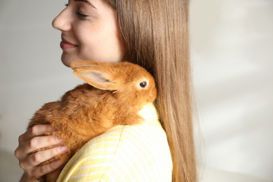 Photo of Young woman with adorable rabbit indoors, closeup. Lovely pet