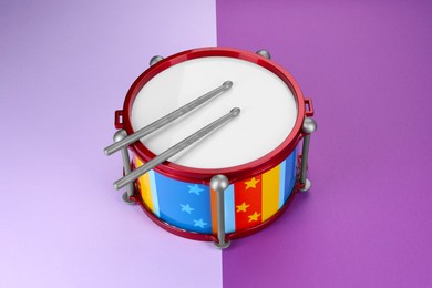 Photo of Children's drum with two drumsticks on color background