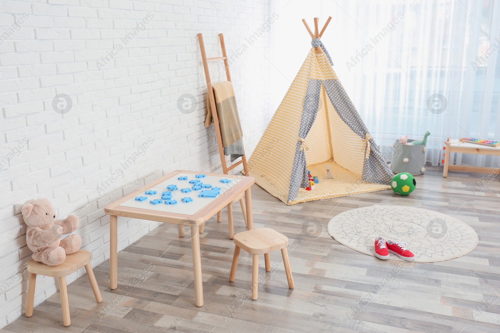 Photo of Cozy kids room interior with table, stools and play tent