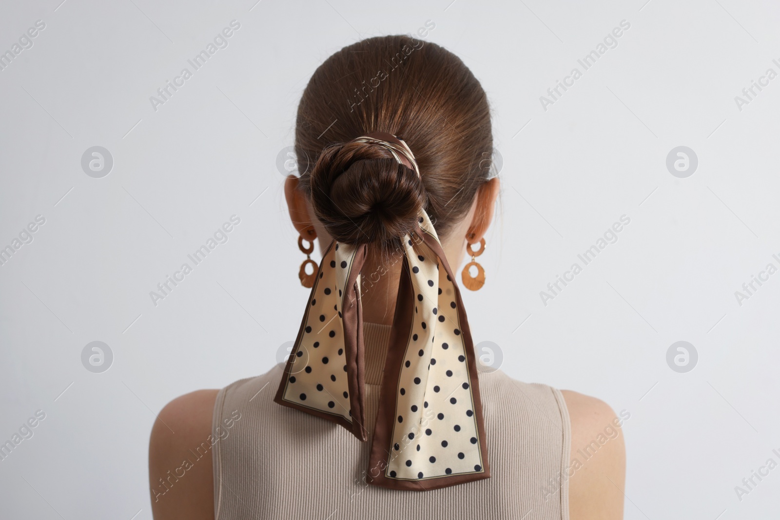 Photo of Young woman with stylish bandana on light background, back view