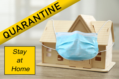 Stay at home during coronavirus quarantine. Wooden house model with medical mask