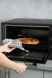 Photo of Woman taking baking pan with delicious pie from electric oven in kitchen, closeup