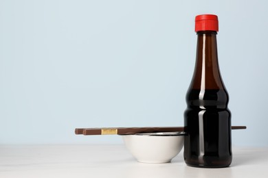 Photo of Soy sauce and chopsticks on white table, space for text