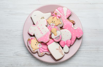 Cute tasty cookies of different shapes on white wooden table, top view. Baby shower party