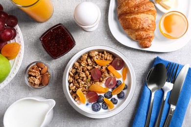 Delicious breakfast with granola served on white table, flat lay