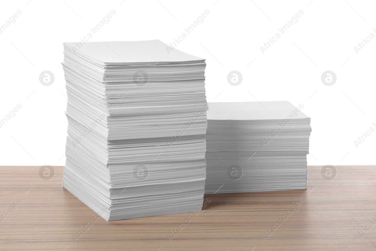 Photo of Stacks of paper sheets on wooden table against white background