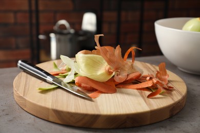 Photo of Peels of fresh vegetables and knife on grey table indoors