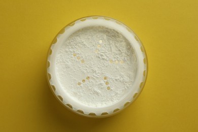 Photo of Rice loose face powder on yellow background, top view. Makeup product