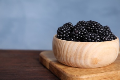 Fresh ripe blackberries in bowl on wooden table, closeup. Space for text