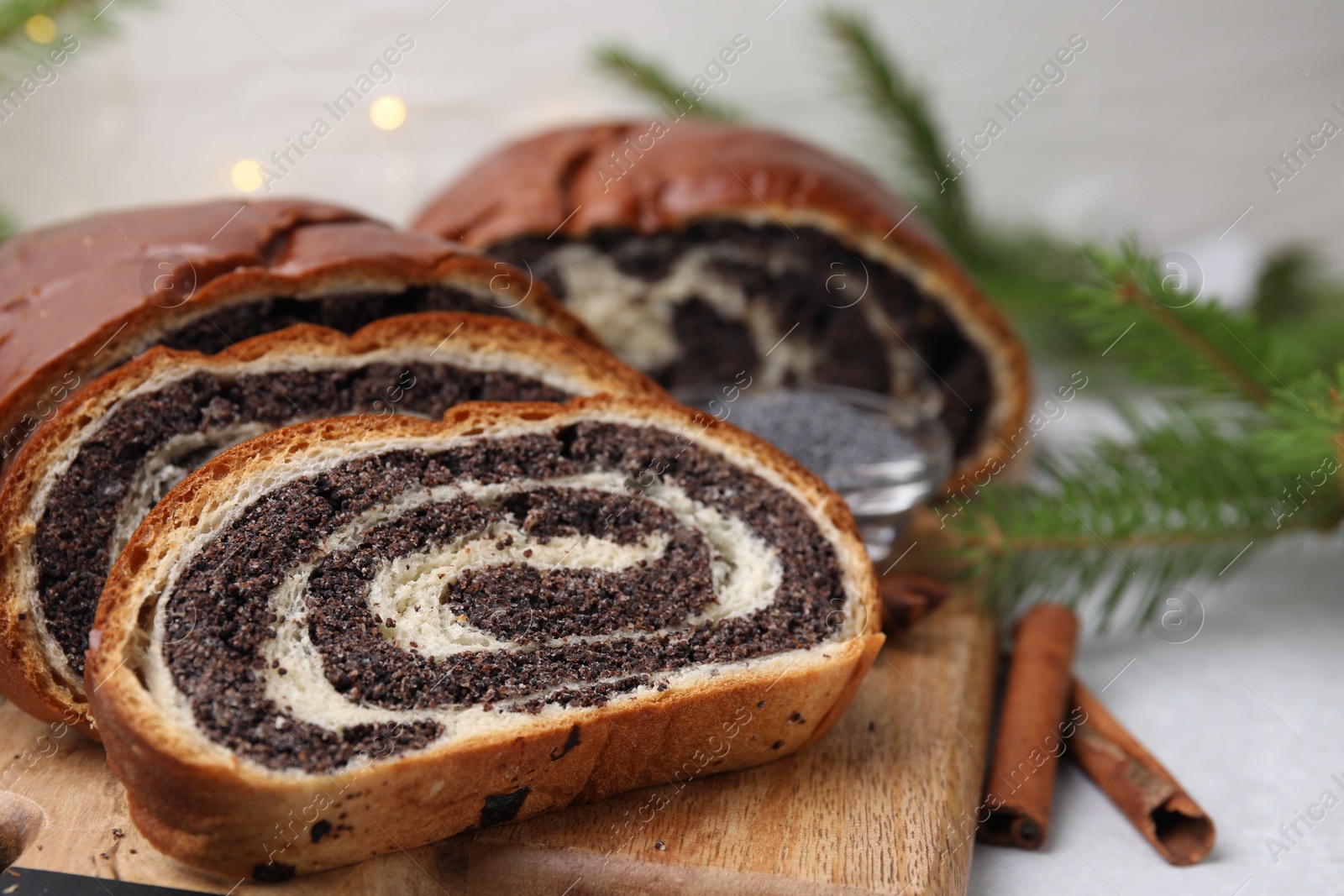 Photo of Cut poppy seed roll and cinnamon sticks on light grey table, closeup with space for text. Tasty cake