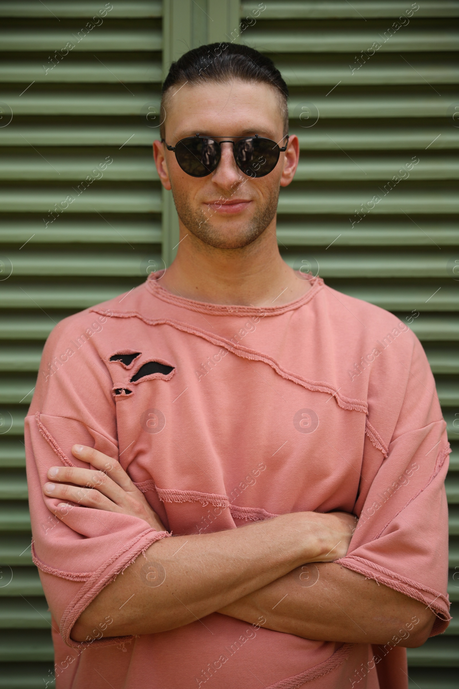 Photo of Handsome young man in stylish sunglasses near shutters