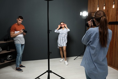 Photo of Professional photographer with assistant taking picture of young man in modern studio