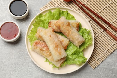 Photo of Delicious fried spring rolls served on grey table, flat lay