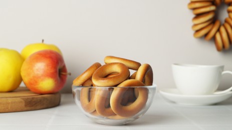 Photo of Bowl with delicious ring shaped Sushki (dry bagels) on white table