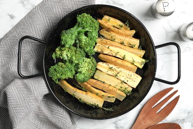 Photo of Flat lay composition with raw white carrot and broccoli in frying pan on white marble table