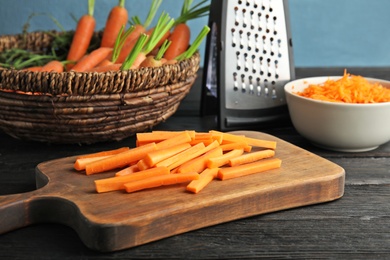 Wooden board with carrot sticks on table