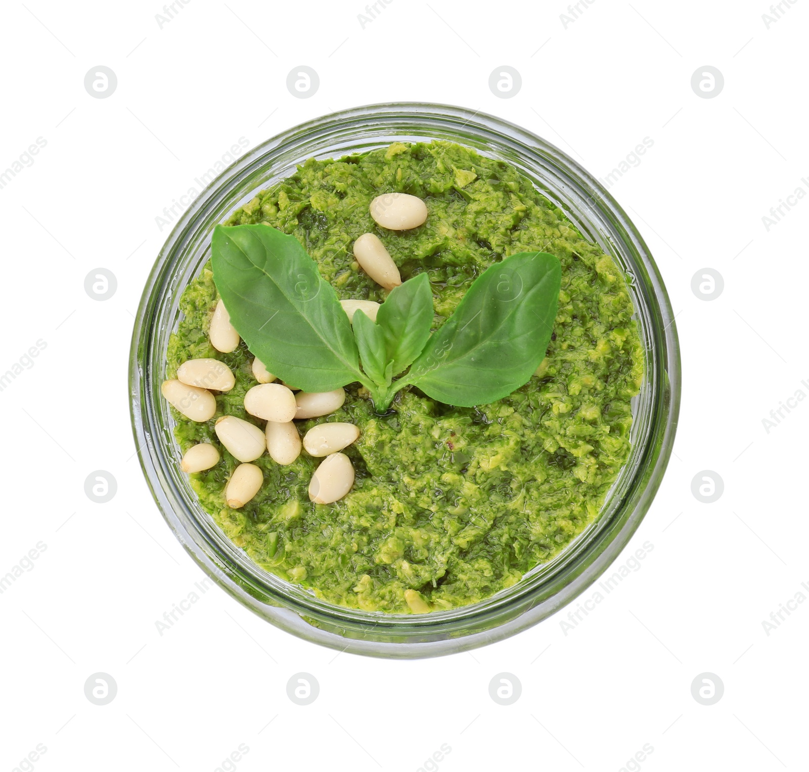 Photo of Jar with delicious pesto sauce, pine nuts and basil leaves isolated on white, top view