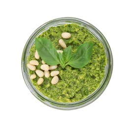 Photo of Jar with delicious pesto sauce, pine nuts and basil leaves isolated on white, top view