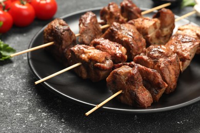 Photo of Skewers with delicious shish kebabs on grey textured table, closeup