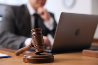 Photo of Notary working with laptop at wooden table, focus on gavel