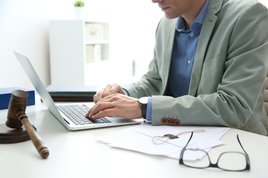 Notary working with laptop and judge gavel on table, closeup. Law and justice concept