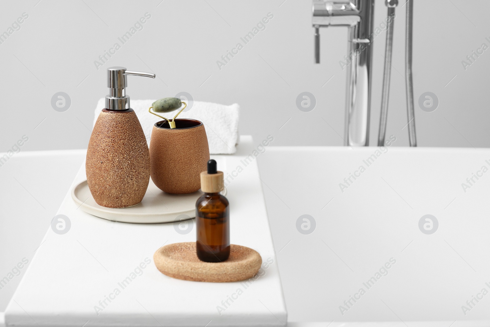 Photo of Different personal care products and accessories on bath tub in bathroom, space for text