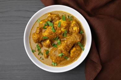 Photo of Delicious chicken with curry sauce on grey wooden table, top view