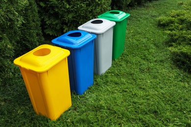 Photo of Many color recycling bins on green grass outdoors, space for text