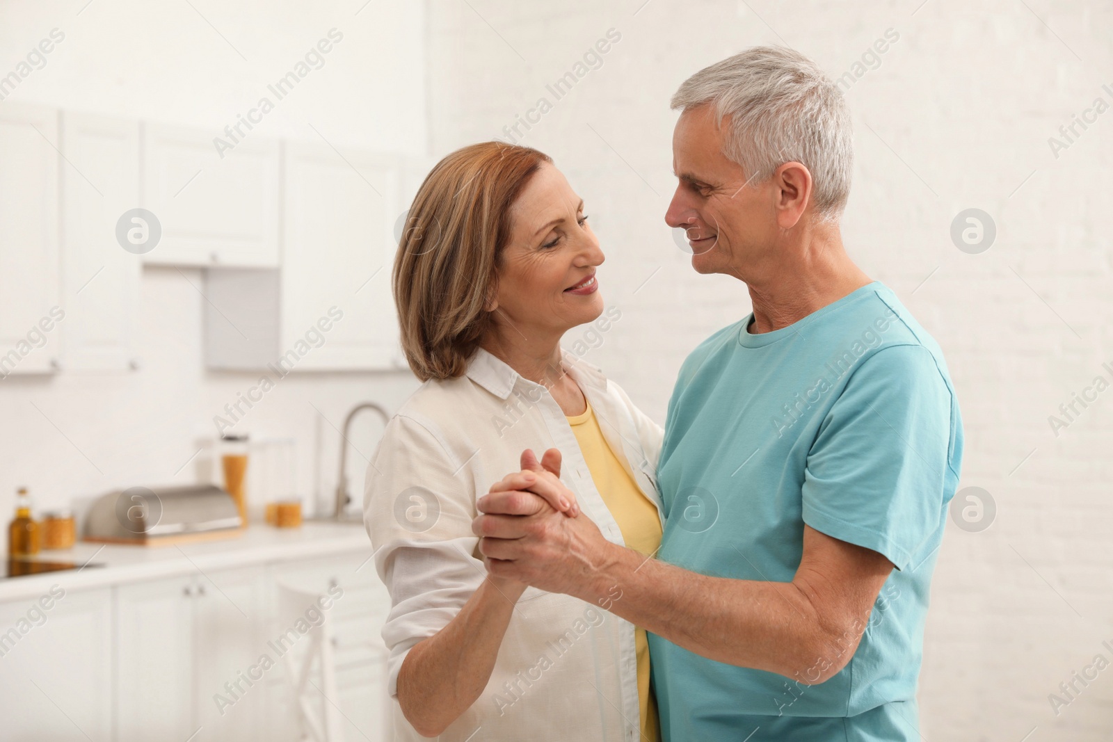 Photo of Happy senior couple dancing in kitchen at home