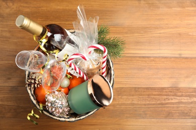 Photo of Basket with Christmas gift set on wooden table, top view. Space for text