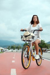 Beautiful young woman riding bicycle on lane in city