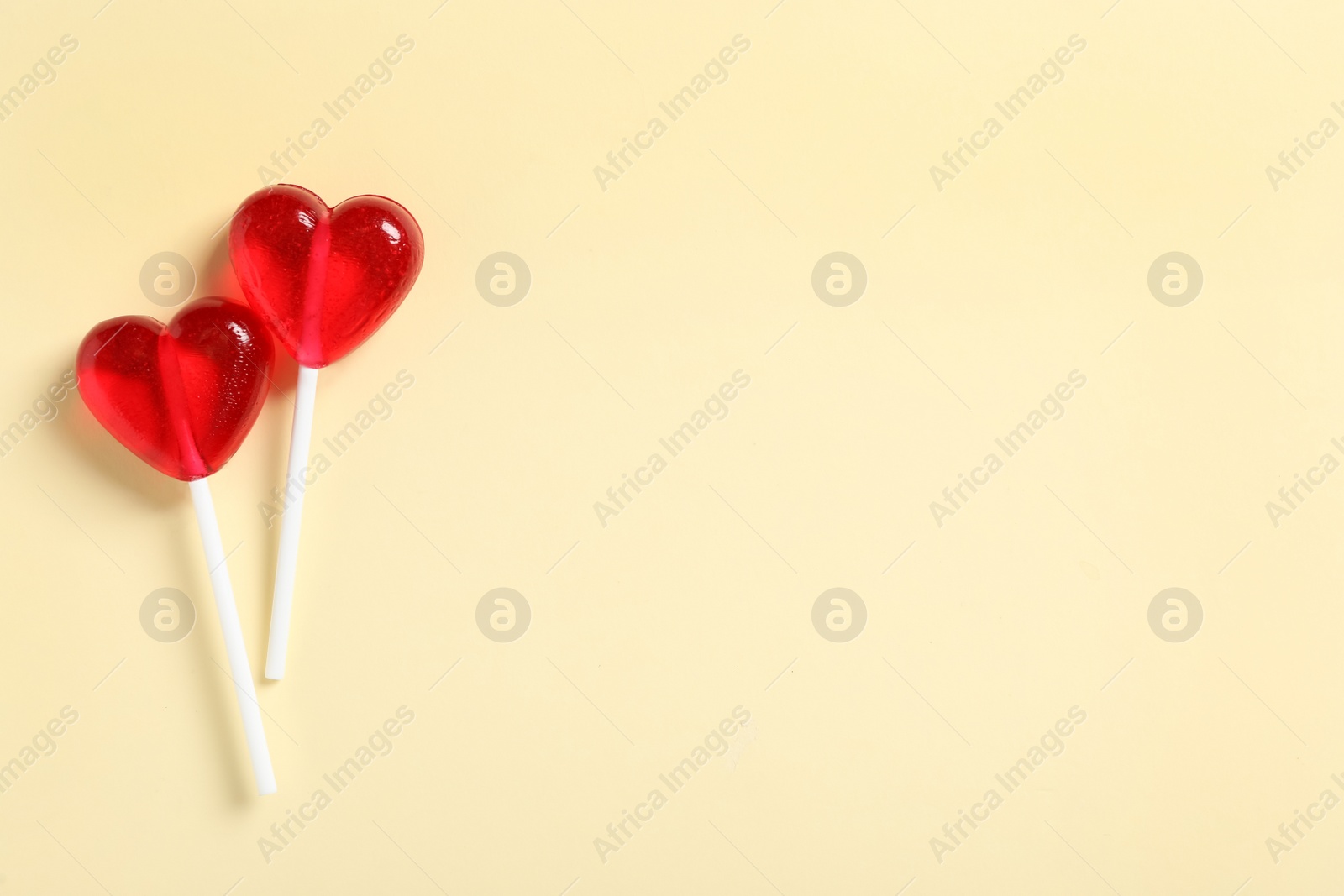 Photo of Sweet heart shaped lollipops on beige background, flat lay with space for text. Valentine's day celebration