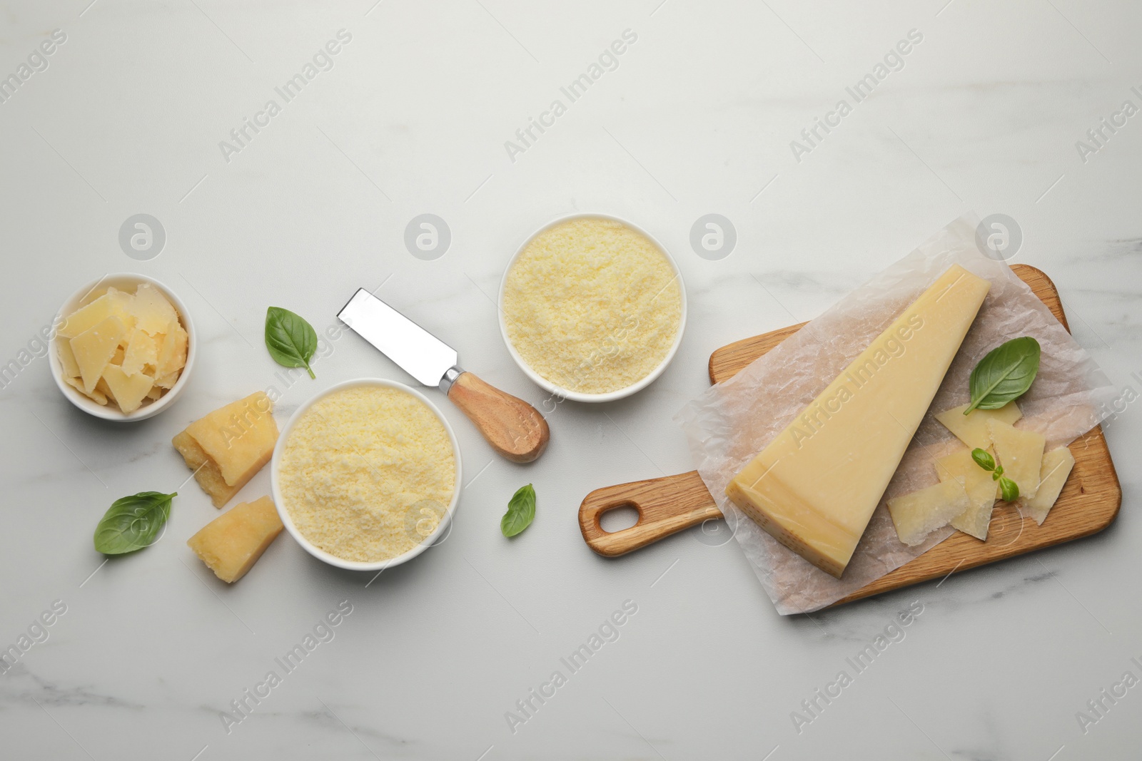 Photo of Flat lay composition with whole and grated parmesan cheese on white marble table