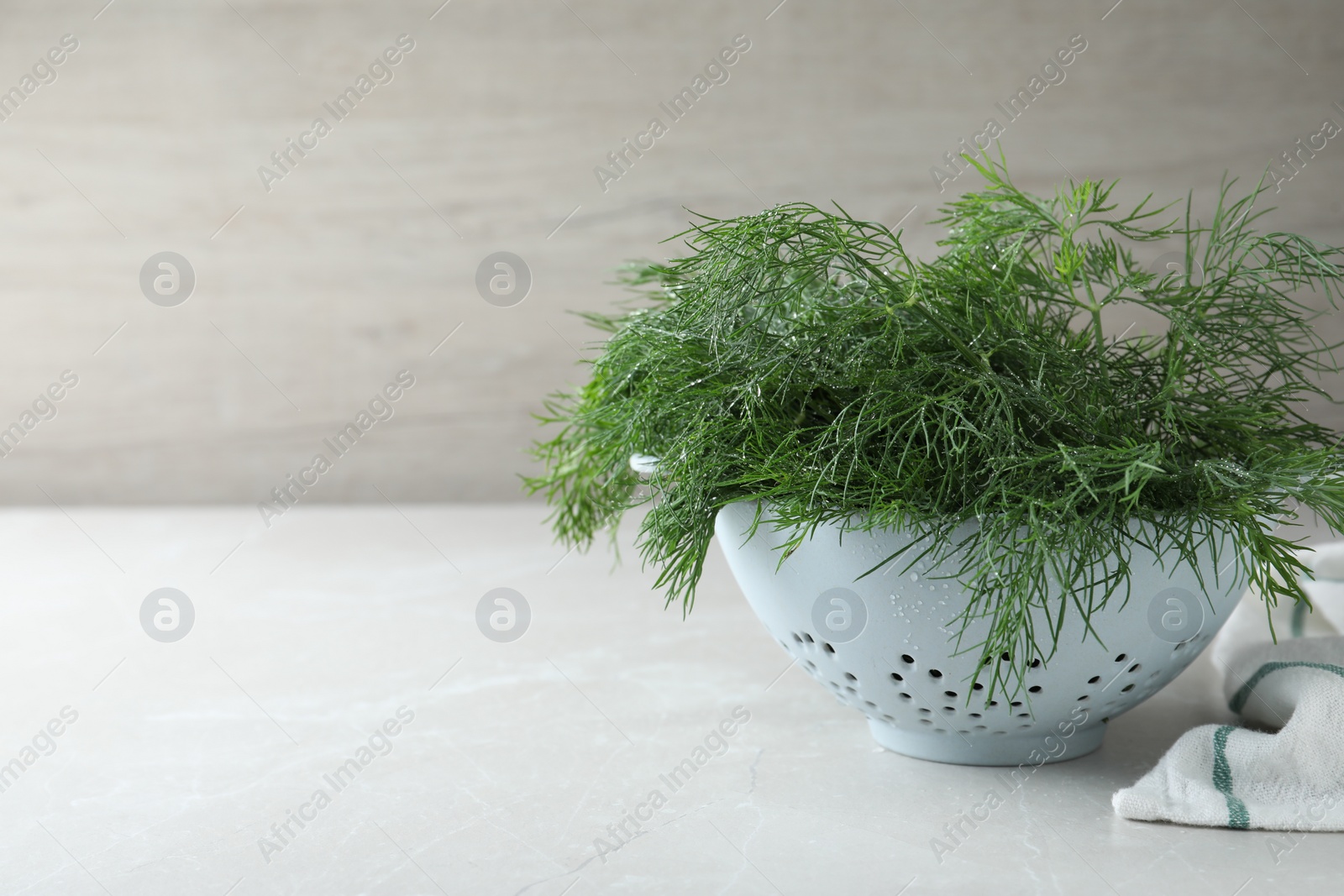 Photo of Fresh dill in colander on white table, space for text